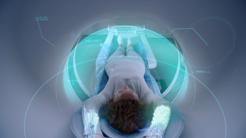 Woman undergoes MRI or CT scan, lies on bed inside the machine. Visual effects of scanning female patient brain and body. High-tech equipment in modern medical lab with augmented reality technologies.